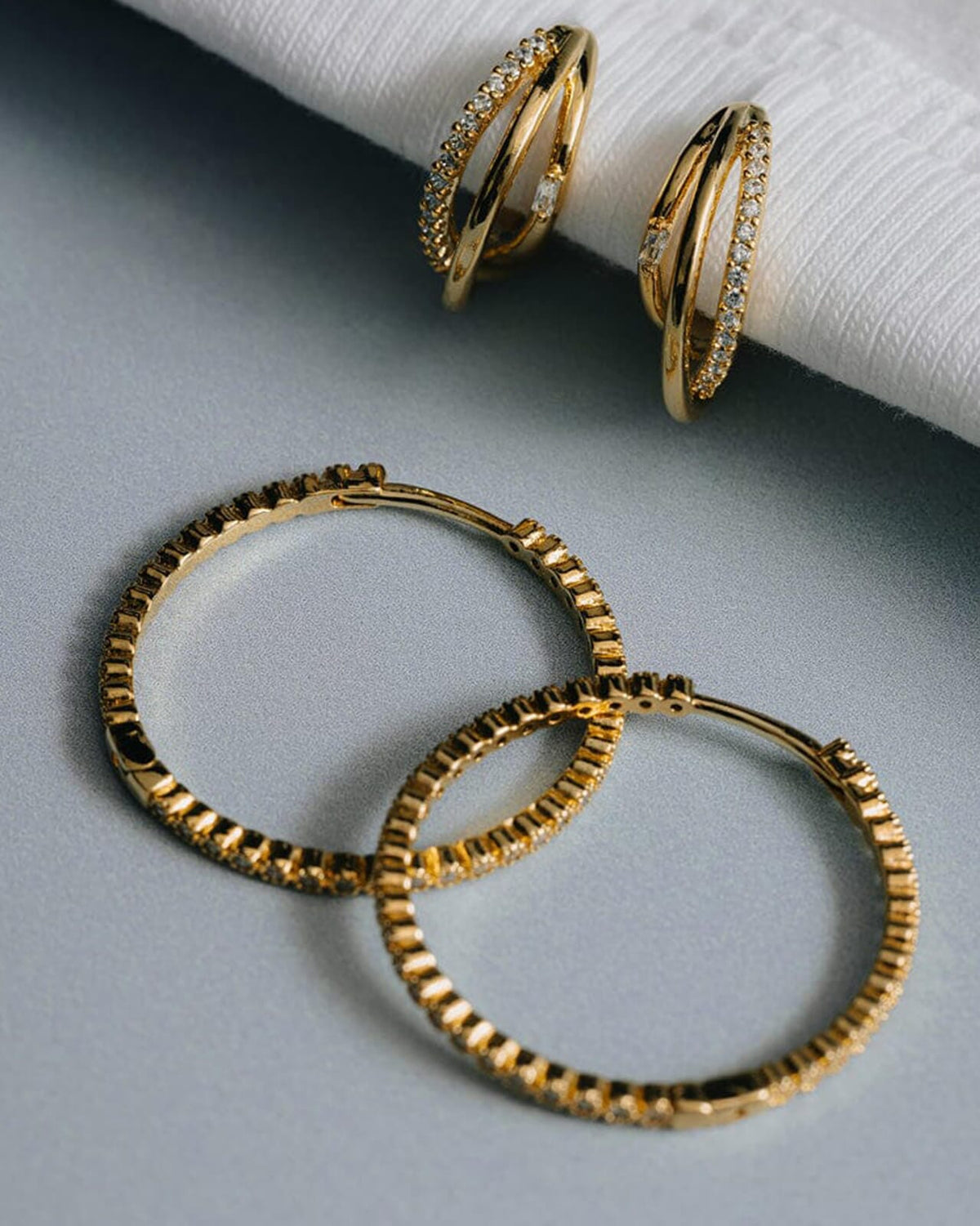 Gullfargede hoops med glitrende stener og praktisk klikklås. Lette øredobber med et tidløst design som passer både til hverdagsbruk og festlige anledninger.